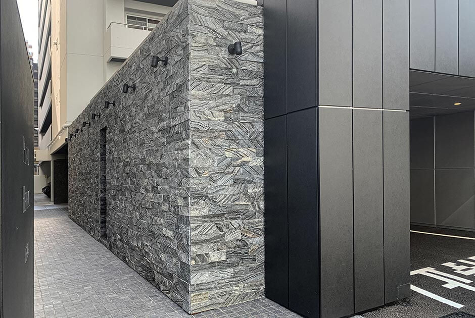 石面タイルと黒色アルマイト処理のバイブレーション仕上げを施したアルミパネルが外壁に使われた